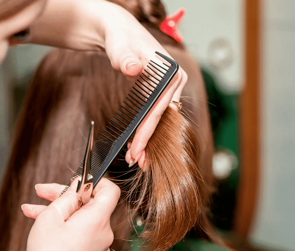Person trimming hair with scissors and comb.