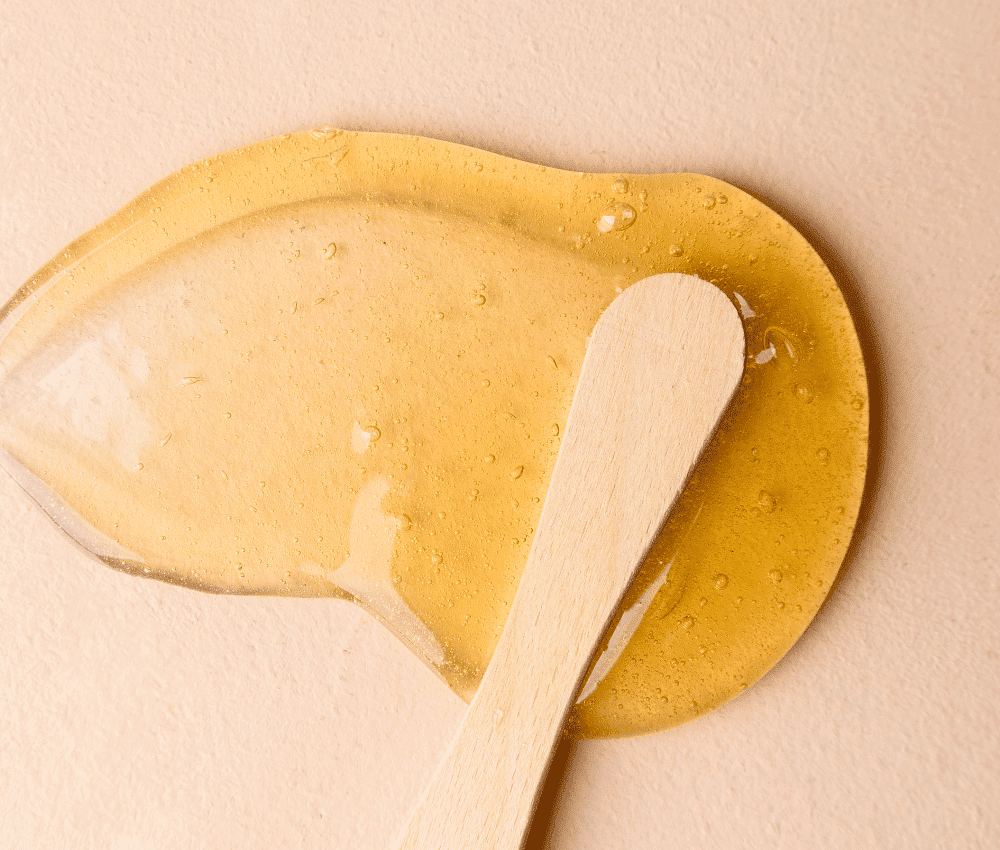 A wooden spoon on a surface with spilled honey.