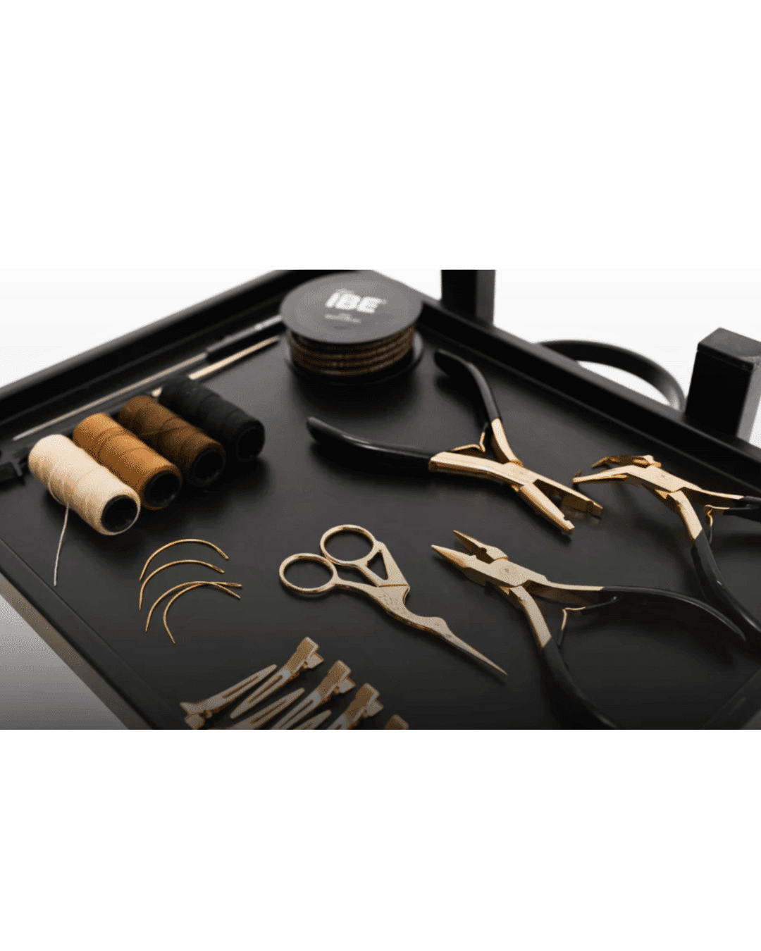 Surgical tools and colored thread arranged neatly on a black tray.