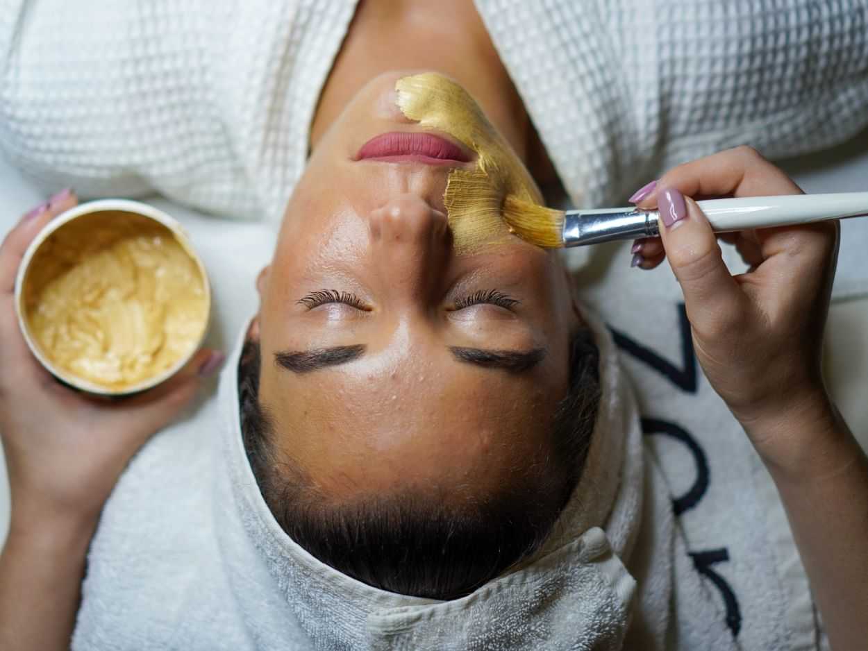 A person receiving a facial mask treatment at a spa.